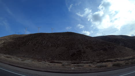 Looking-out-the-passenger-window-at-wind-turbines-on-a-hillside---point-of-view