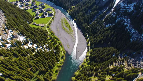 aerial view of a river winding through a forested mountain valley with a small town