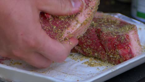 dos manos frotan especias y sal en un filete de costilla grueso y crudo preparándolo para ser asado