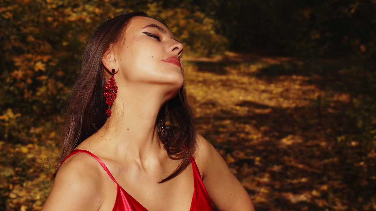 Bellezza accattivante in autunno: un ritratto di grazia ed eleganza tra le foglie dorate, che celebra la natura e la serenità in un vibrante abito rosso
