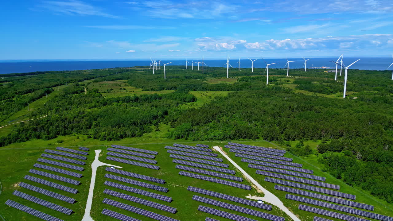 Aerial drone shot over solar panels with windmills in the background in Paldiski Wind Park, Pakri peninsula, Estonia, Europe