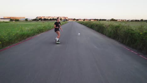 aerial shot of someone cruising on a onewheel through a grassy field, dog by their side