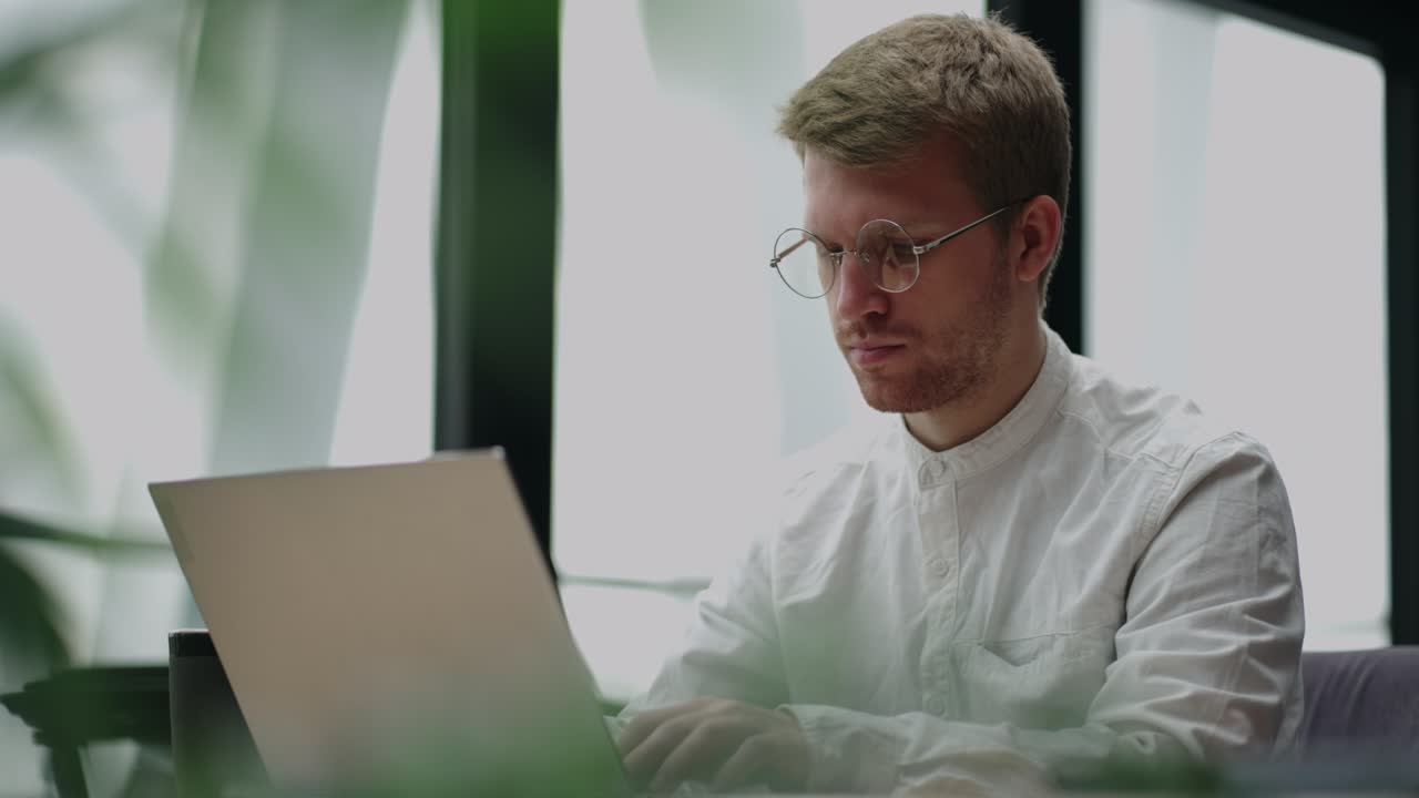 office worker is sending emails and making report in laptop, portrait in office of large successful company