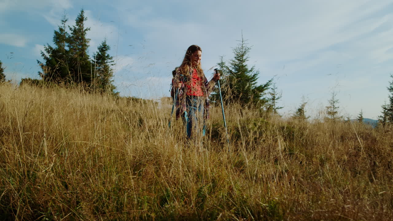 Woman hiking with trekking poles in mountains