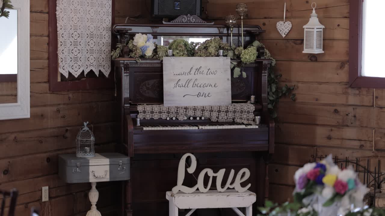 lugar de recepción de bodas decoración rústica de un signo de amor, piano, varias flores y decoraciones con velas
