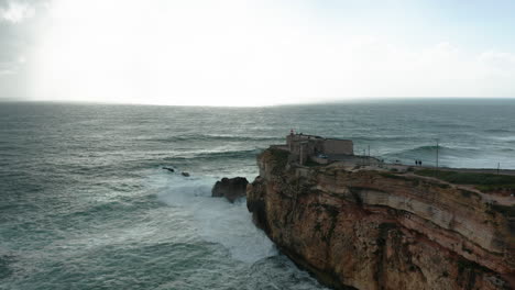 beautiful aerial of the old fortress fort of são miguel arcanjo (st. michael the archangel) at the edge of cliff with a wild sea