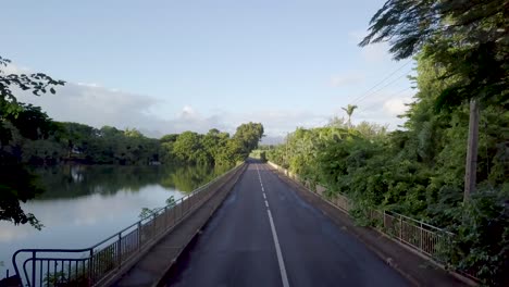 road passing by beautiful calm lake surrounded by forest on sunny warm day