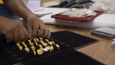 Un-Comerciante-Reorganizando-Joyas-De-Oro-De-Diseñador-Contrastadas-Y-Anillos-De-Boda