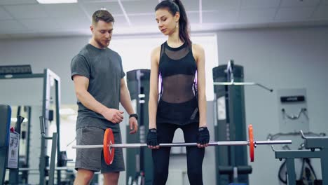 athletic girl with a perfect body lifting metal barbell. personal fitness instructor. personal training.