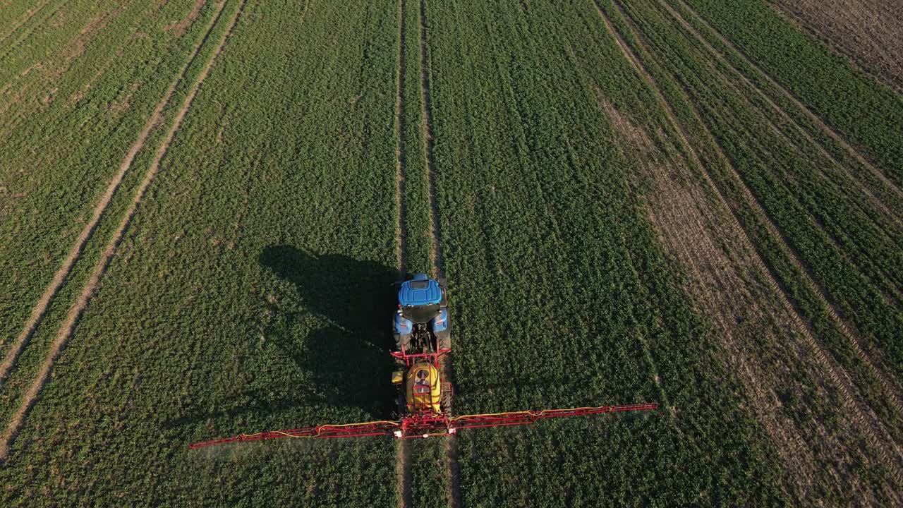 Tractor spray fertilizer on agricultural field, aerial view
