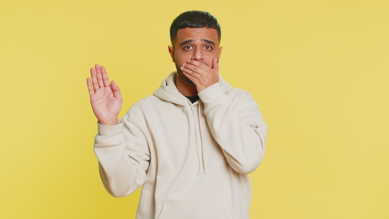 Frightened indian man closing mouth with hands refusing to tell terrible secret unbelievable truth