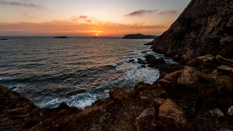 Playa-De-La-Costa-Contra-El-Oleaje-Del-Océano-Y-La-Puesta-De-Sol-En-Un-Lapso-De-Tiempo-De-Cielo-Naranja-Sin-Límites