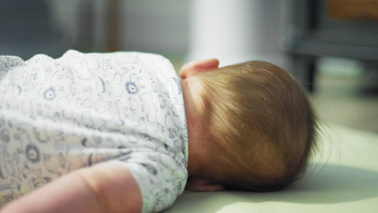 아기 소년이 배에서 등으로 굴러가려고 합니다.