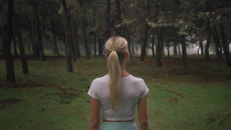 Behind-lost-fit-woman-standing-in-mysterious-forest,-looking-at-enchanted-woods