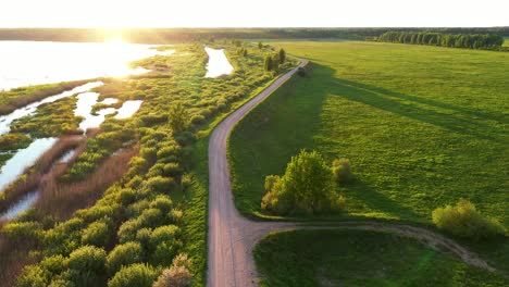 Luftaufnahme-Des-Langen-Weges,-Der-Während-Des-Goldenen-Sonnenaufgangs-über-Das-Grüne-Sumpfgebiet-Absteigt