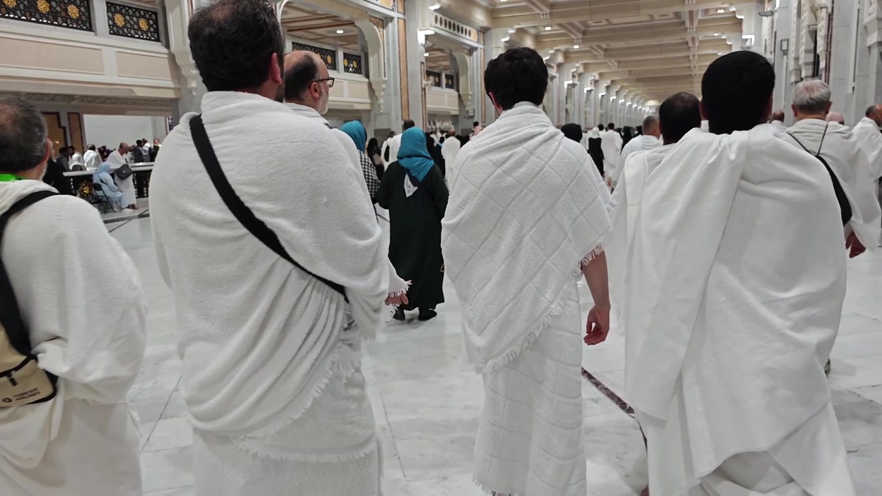 Pellegrini che camminano con indumenti Ihram all'interno della Grande Moschea alla Mecca