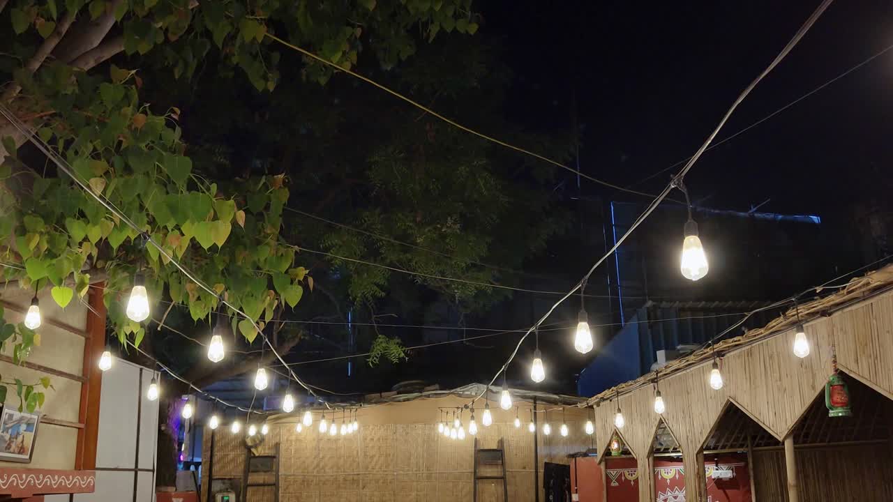Steady shot of a decorated yellow glowing light bulbs at night
