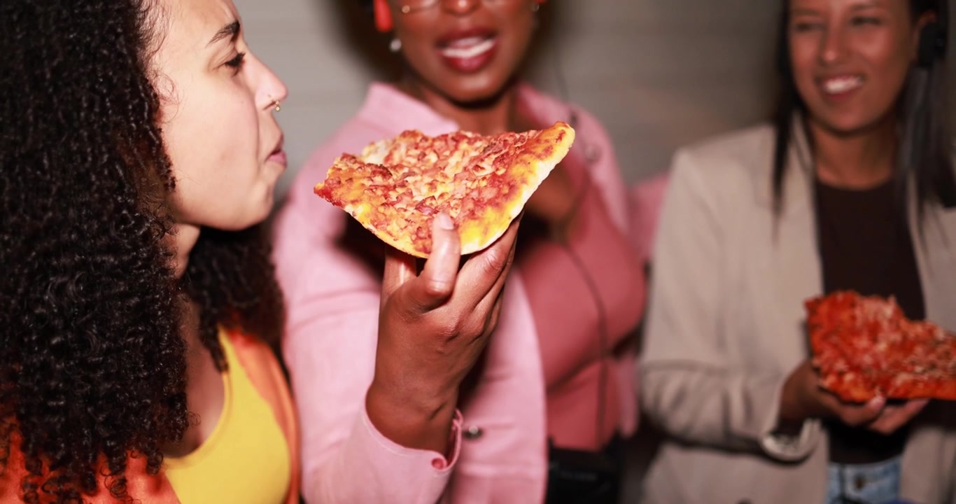 Donne diverse felici che gustano fette di pizza a un incontro sociale