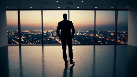businessman looking at city skyline from office window at dusk