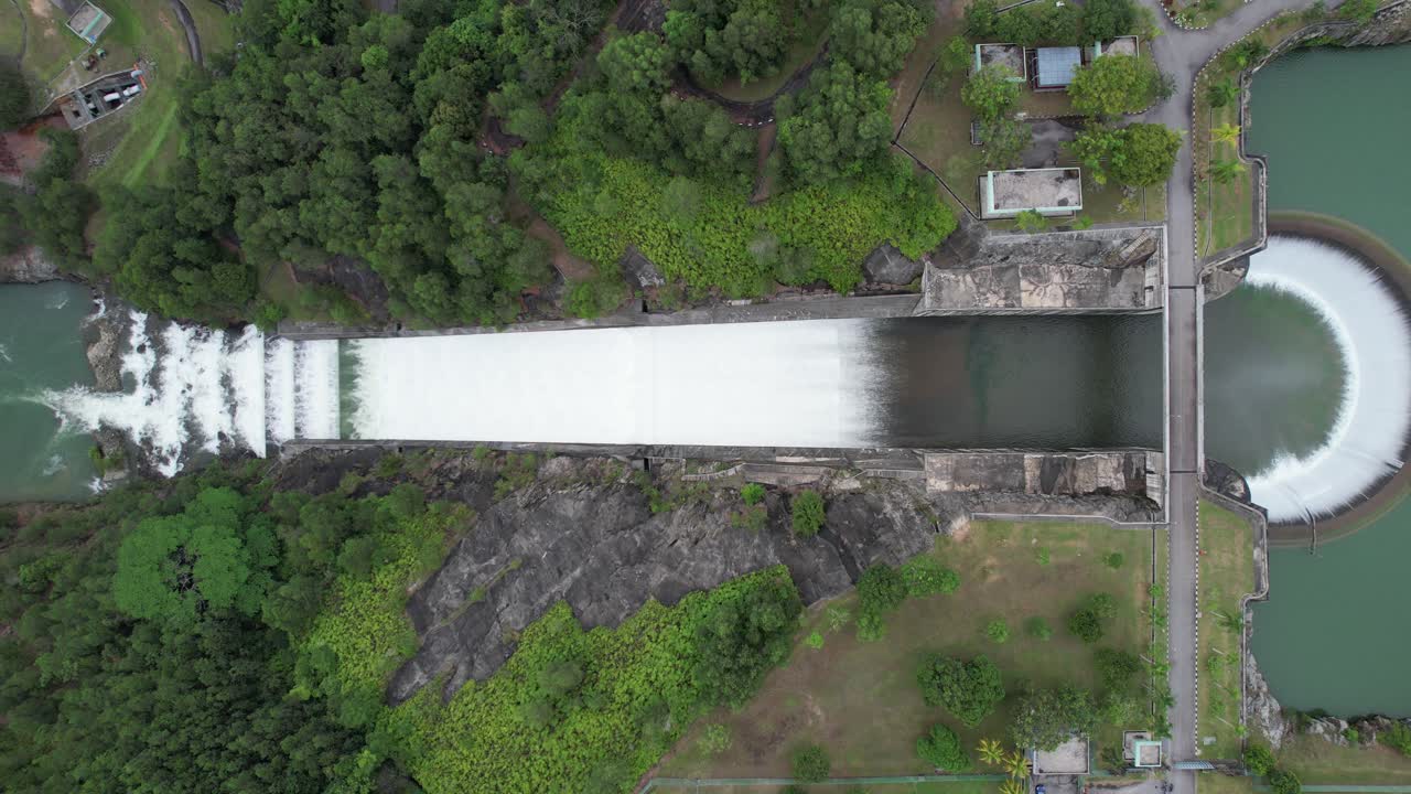 Cinematic aerial footage drone of Dam Spillway to River of Sungai Selangor Dam in Malaysia, showcasing its majestic spillway and vast reservoir surrounded by lush greenery. Captured in 4K resolution.