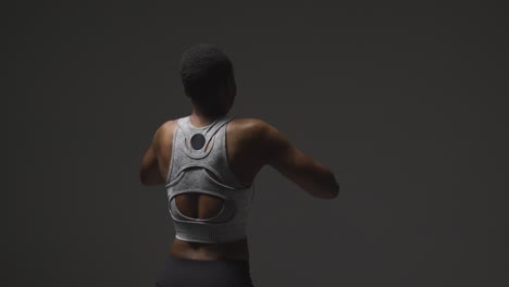 Rear-View-Studio-Shot-Of-Young-Woman-Wearing-Gym-Fitness-Clothing-Warming-Up-For-Exercise