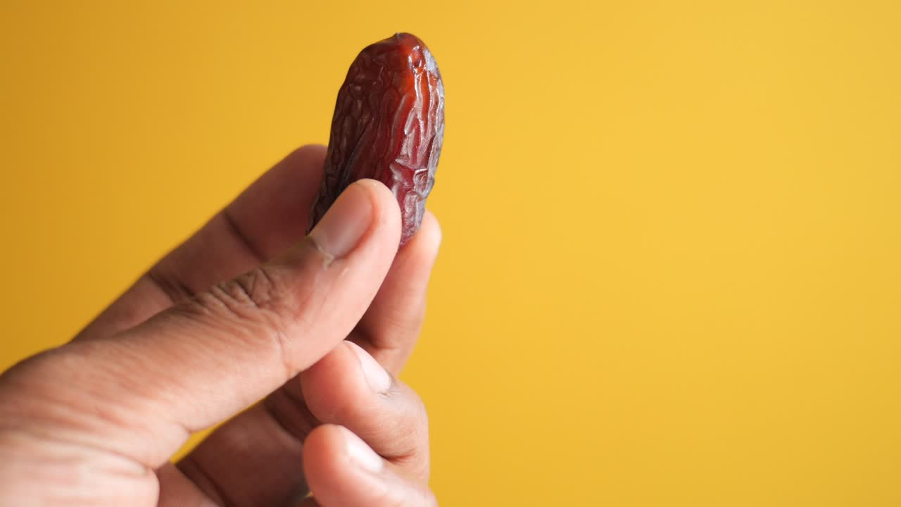 mano sosteniendo una sola fecha contra un fondo amarillo