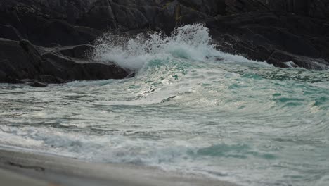 powerful waves are crashing on the rocky shore