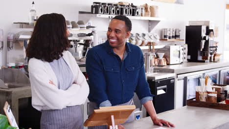 mixed race couple behind the counter at their coffee shop