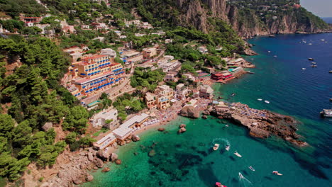 A-cinematic-aerial-shot-of-the-beautiful-cliffs-and-beach-landscape-of-Marina-Piccola-on-the-island-of-Capri,-a-popular-tourist-destination-along-the-Amalfi-Coast-in-the-Bay-of-Naples-in-Italy