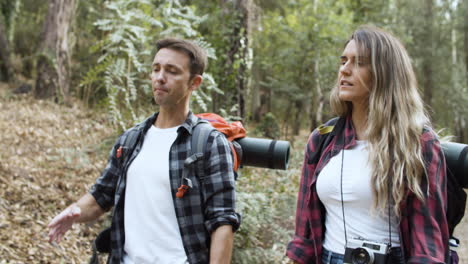 couple of travelers with backpacks walking on forest path