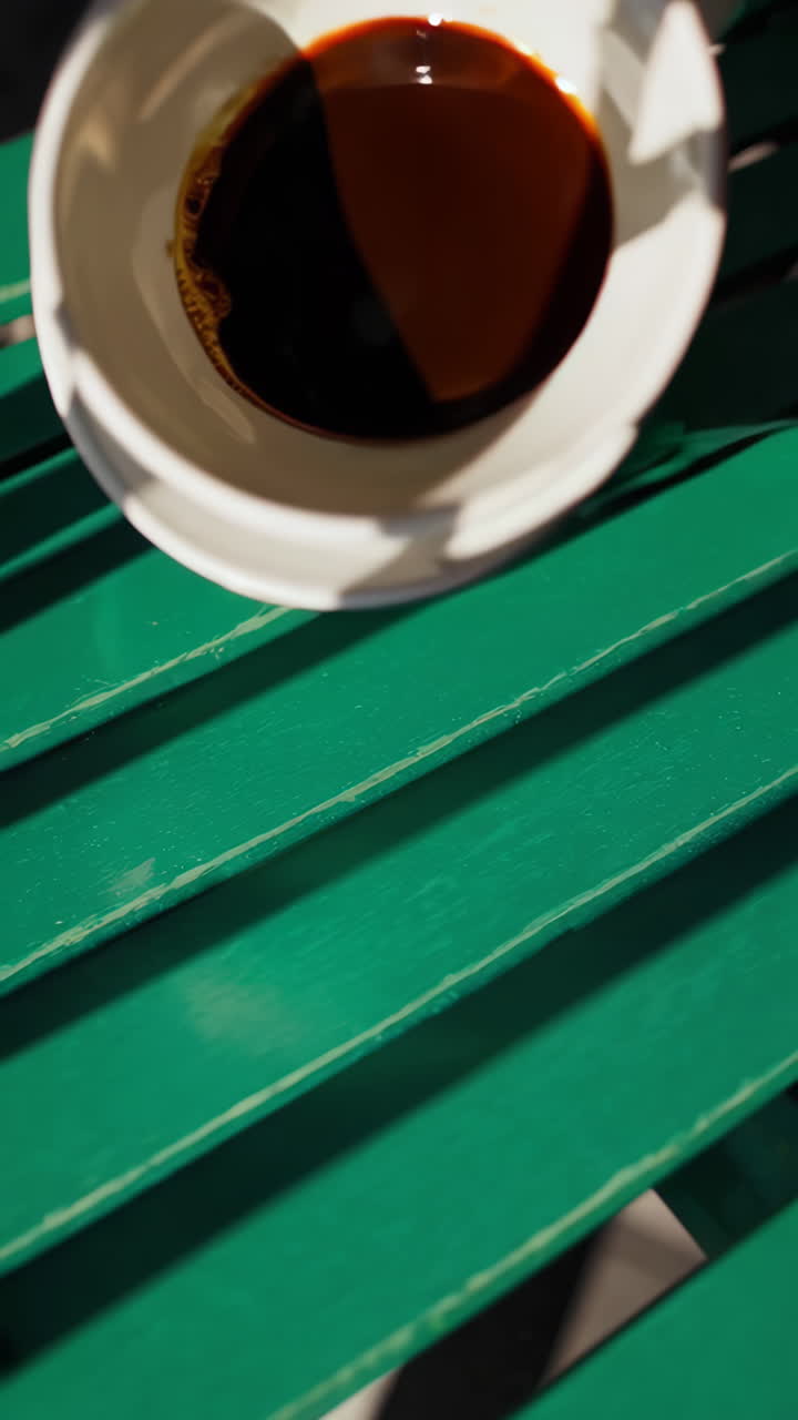 A white coffee cup with spilled coffee on a green table, with a hand stirring in one image