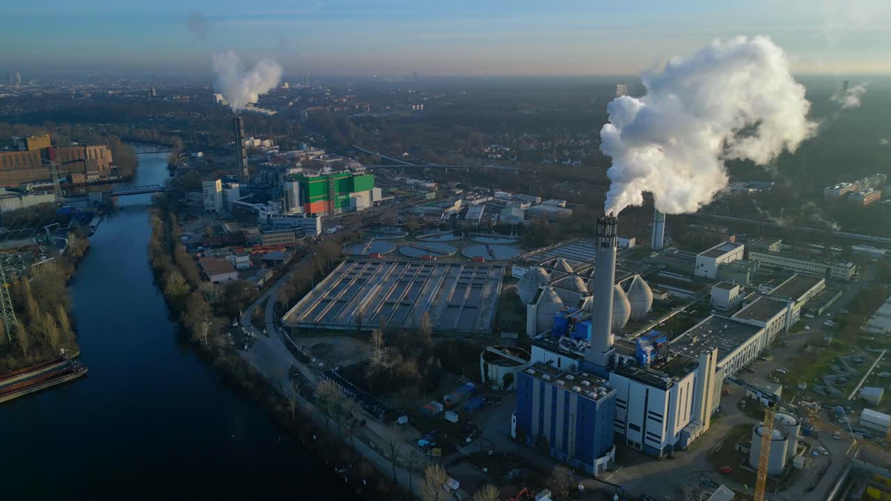 Impianto di termovalorizzazione dei rifiuti urbani con grandi ciminiere che emettono vapore in un cielo azzurro, che illustra lo sviluppo urbano sostenibile. Bella vista aerea, panorama dall'alto, panoramica con drone