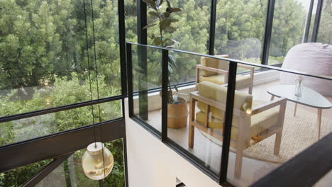 modern home room with glass walls, cozy seating area, and lush greenery outside, copy space