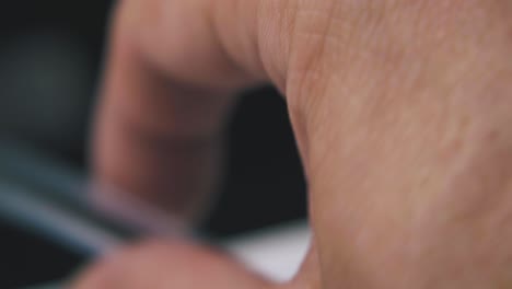 person holds modern ball pen on dark blurred background