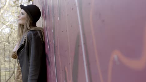 stylish woman posing beside graffiti wall