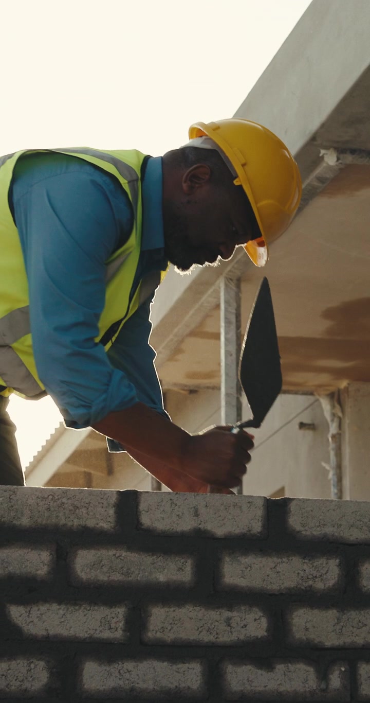 Construction Worker Laying Bricks on a Building Site