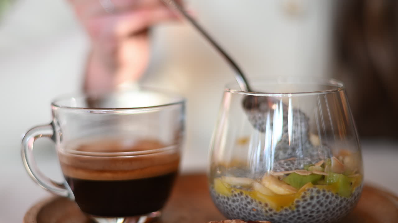 Woman eating chia seeds pouding with mango and black coffee at a restaurant