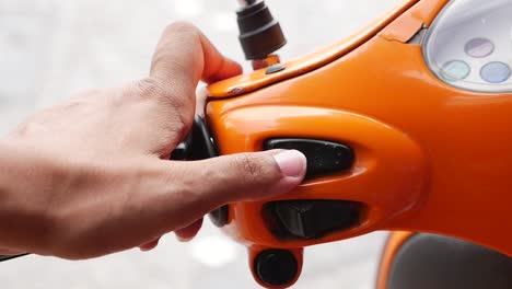 a person's hand on the handlebars of an orange motorcycle