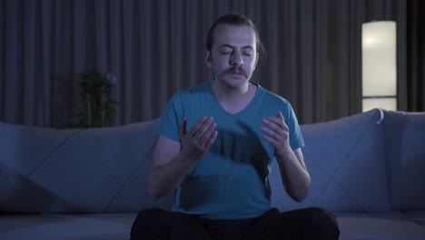 young man praying at home at night.