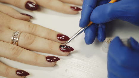 manicurist attaching rhinestones on nails. manicure in beauty salon.