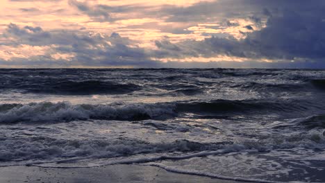 waves at sea during a thunderstorm at sunset