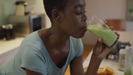 Retrato-De-Una-Mujer-Atractiva-Afroamericana-Sonriente-Bebiendo-Batido-Casero-En-La-Cocina