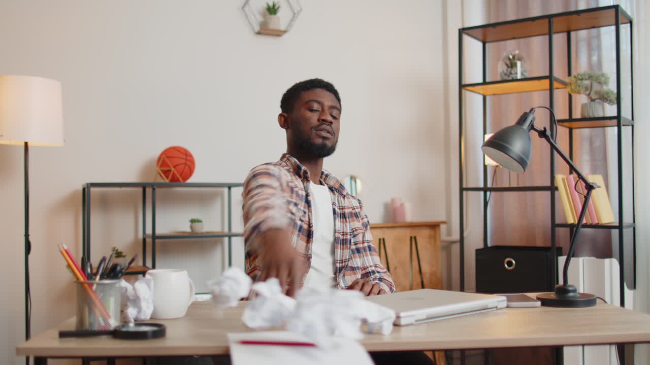Angry furious man working at home office throwing crumpled paper having nervous breakdown at work