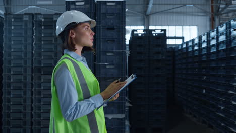 woman storehouse employee noting shipment details examining factory warehouse