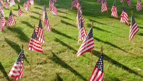 Cerca-De-Las-Banderas-De-Estados-Unidos-Ondeando-En-El-Viento-Y-Proyectando-Una-Sombra-Sobre-El-Césped-Verde