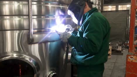 worker welding stainless steel tank, using tig, mig welder, close up, dolly, slide, movement