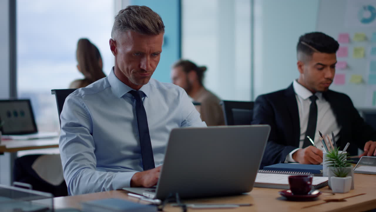 hombre de negocios serio escribiendo en una computadora portátil en un espacio abierto. ejecutivo masculino usando una computadora portátil