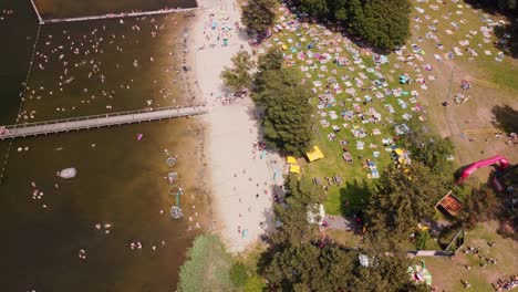 gran multitud disfrutando del clima de verano en la playa del lago local.