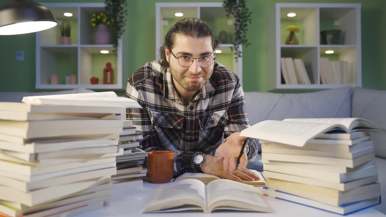 estudiante masculino feliz estudiando en el escritorio y mirando a la cámara sonriendo.