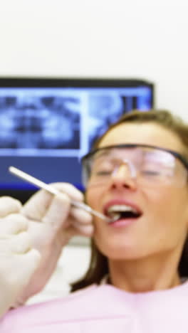 dentist examining a female patient with tools